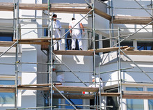 Foto: Bauarbeiter auf der Rüstung beim streichen der Fassade